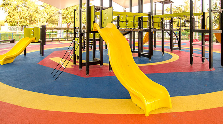 shaded playground activity tower equipment with colorful rubber floor