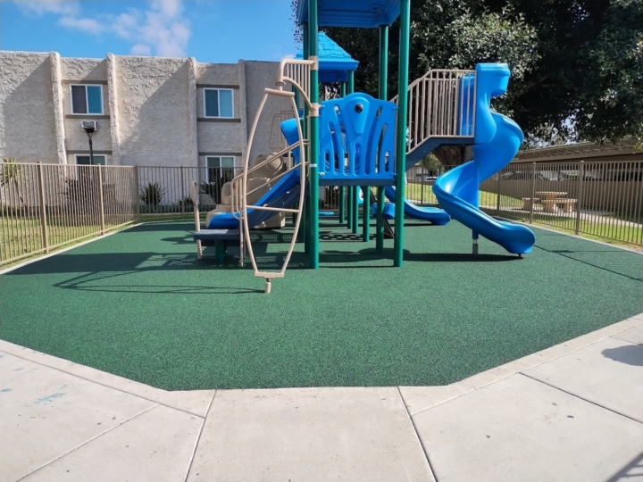 playground equipment with a dark green rubber safety surface